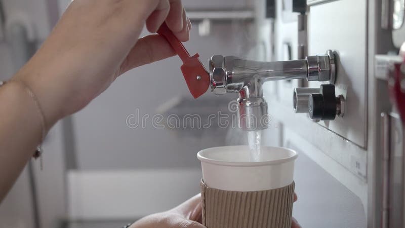 Équipage de cabine féminin en injectant de l'eau chaude dans le godet de papier recouverte d'un manchon de tasse dans l'office arr clips vidéos