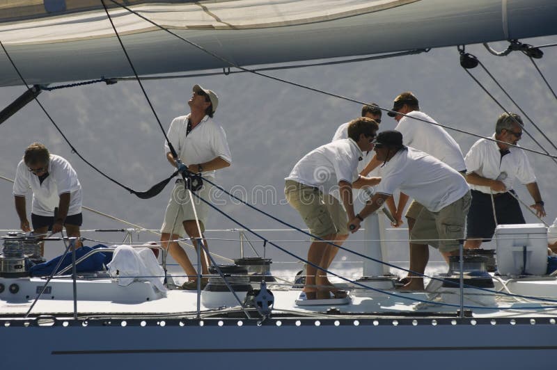 Side view of crew members working on sailboat. Side view of crew members working on sailboat