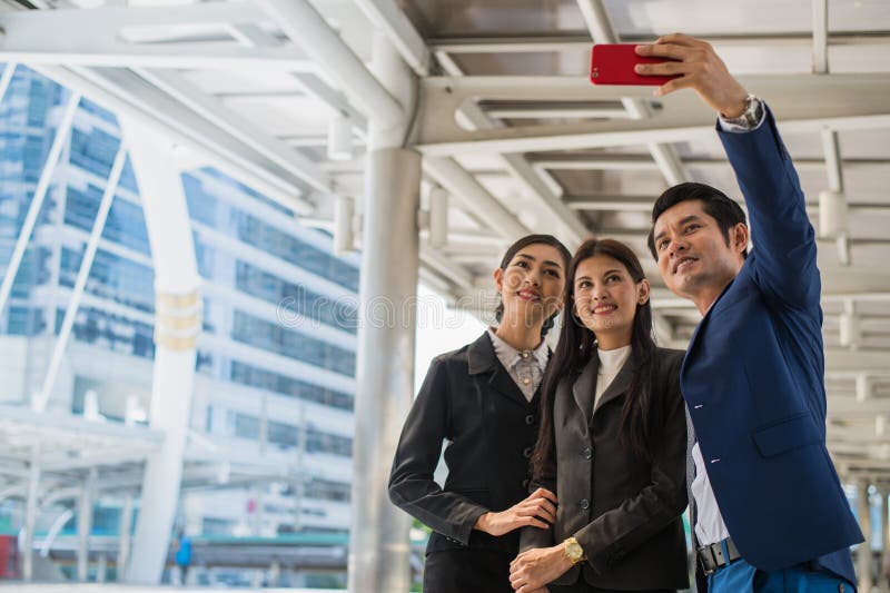 Équipe asiatique d'affaires prenant un selfie avec le smartphone dans la ville images stock Équipe asiatique d'affaires prenant un selfie avec le smartphone dans la ville images stock