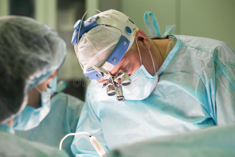 Équipe chirurgicale pendant l'exécution de la chirurgie esthétique dans l'ope d'hôpital photo stock Équipe chirurgicale pendant l'exécution de la chirurgie esthétique dans l'ope d'hôpital photo stock