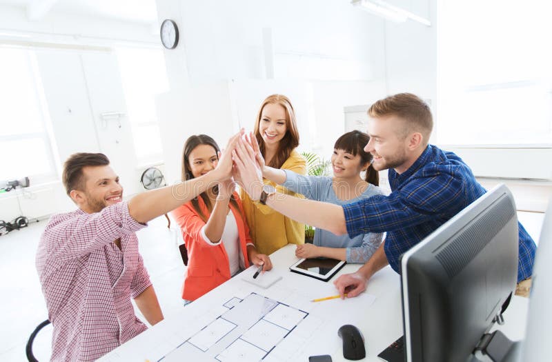 Équipe créative faisant la haute cinq au bureau photo stock Équipe créative faisant la haute cinq au bureau photo stock