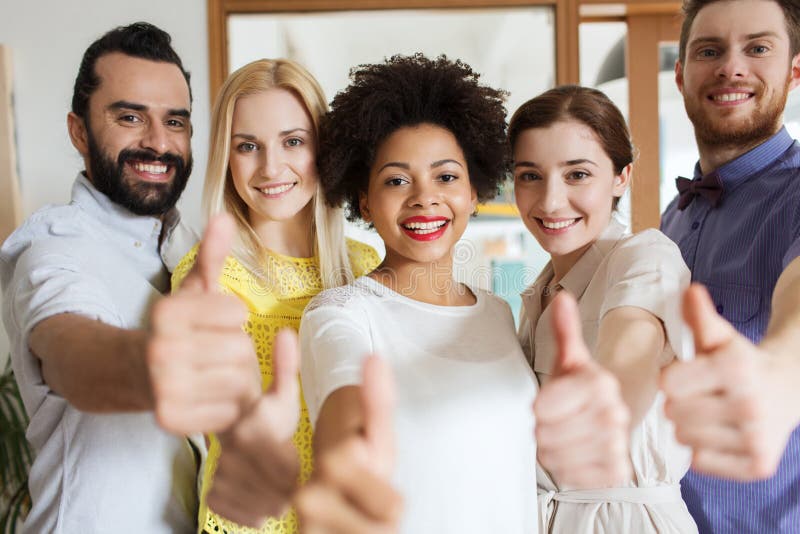 Équipe créative heureuse montrant des pouces dans le bureau images stock