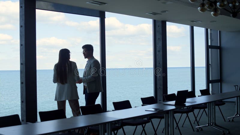 équipe d'affaires discutant des idées à la belle fenêtre vue mer. deux gestionnaires clips vidéos