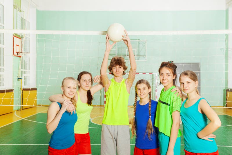 Équipe de volleyball se tenant avec la boule à côté du filet photographie stock Équipe de volleyball se tenant avec la boule à côté du filet photographie stock