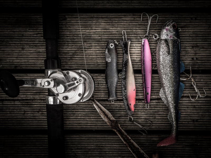 Fishing equipment including pilkers hooks, fishing tackles, rod and a plier on a wooden landing stage. Fishing equipment including pilkers hooks, fishing tackles, rod and a plier on a wooden landing stage