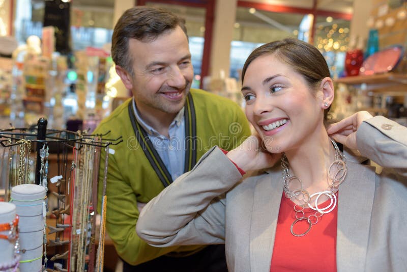 Équipez attacher le collier au cou de filles dans le magasin de détail image libre de droits Équipez attacher le collier au cou de filles dans le magasin de détail image libre de droits