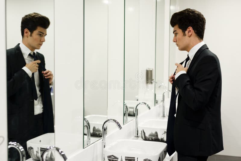 Équipez l'obtention habillée dans des toilettes publiques avec le miroir photo stock