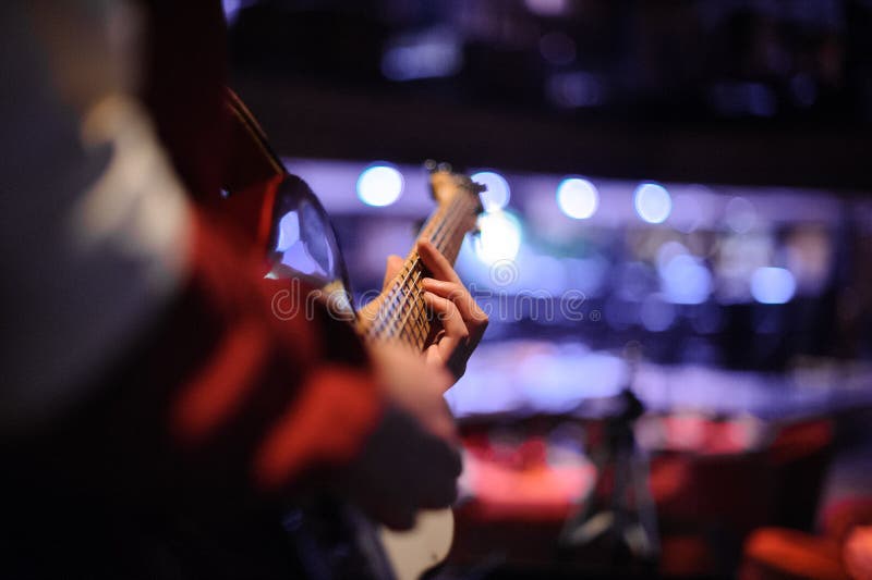Équipez la position dans la boîte de nuit avec une guitare dans des ses mains image libre de droits Équipez la position dans la boîte de nuit avec une guitare dans des ses mains image libre de droits