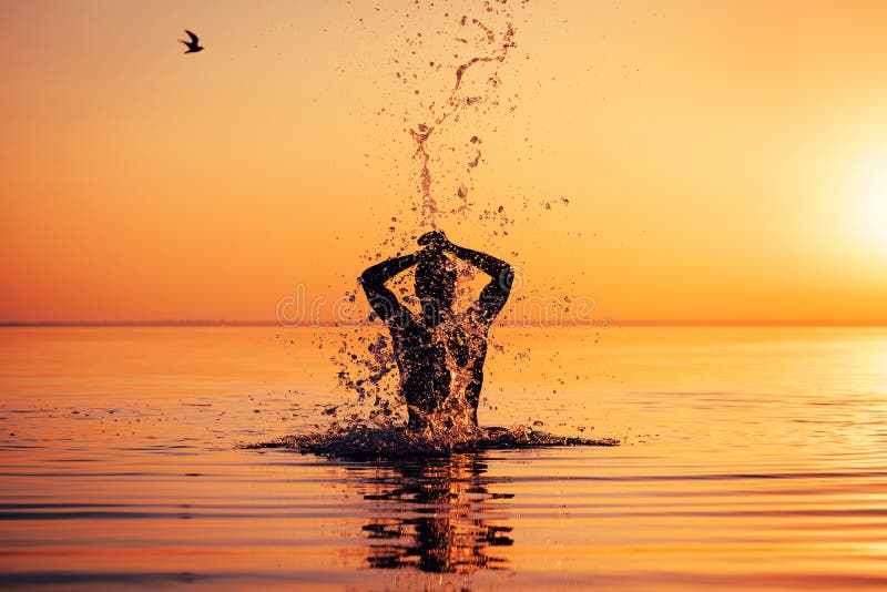 Équipez la silhouette du ` s dans l'eau calme au coucher du soleil photos stock Équipez la silhouette du ` s dans l'eau calme au coucher du soleil photos stock