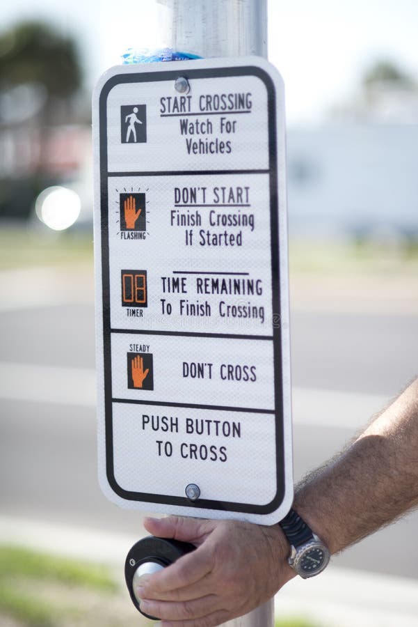 Man pushes the button on a crosswalk signal. Man pushes the button on a crosswalk signal