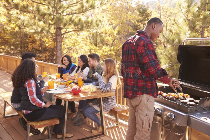 Équipez les barbecues pour des amis à une table, sur une plate-forme dans une forêt images stock Équipez les barbecues pour des amis à une table, sur une plate-forme dans une forêt images stock