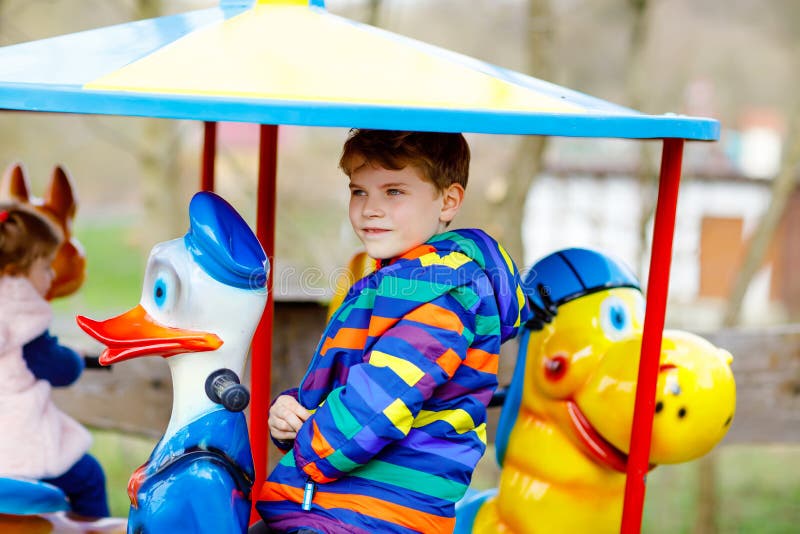 Équitation adorable de garçon d'enfant sur l'animal sur le carrousel de rond point en parc d'attractions Écolier en bonne santé h image stock Équitation adorable de garçon d'enfant sur l'animal sur le carrousel de rond point en parc d'attractions Écolier en bonne santé h image stock
