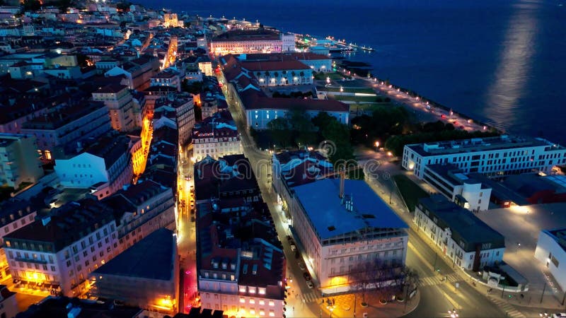 établissant une vue aérienne de la vieille ville illuminée de lisbonne et de la rivière tagus la nuit. heure bleue. portugal. dron