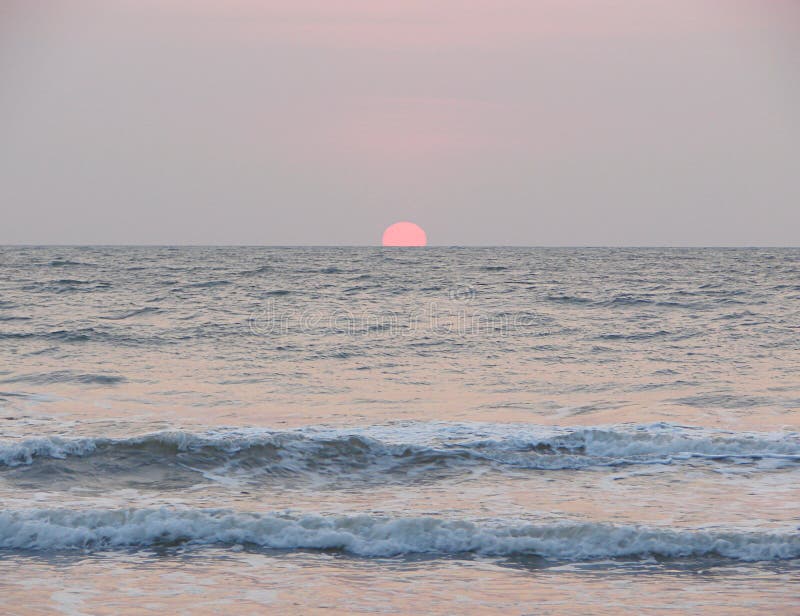 Établissement de Sun rouge à l'horizon au-dessus de la mer à la plage de Payyambalam, Kannur, Kerala, Inde image stock Établissement de Sun rouge à l'horizon au-dessus de la mer à la plage de Payyambalam, Kannur, Kerala, Inde image stock