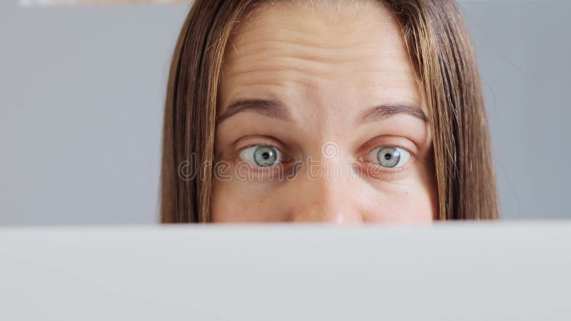 étonnante étonnée femme aux cheveux foncés utilisant un ordinateur portable isolé sur fond gris regardant l'écran d'ordinateur por clips vidéos
