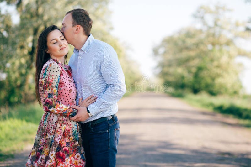 Étreindre sensuel de beaux jeunes couples et embrasser sur la route en soleil parmi le gisement et les arbres de ressort Famille images stock Étreindre sensuel de beaux jeunes couples et embrasser sur la route en soleil parmi le gisement et les arbres de ressort Famille images stock