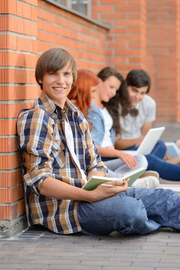 Studying boy with college friends sitting on ground outside campus. Studying boy with college friends sitting on ground outside campus