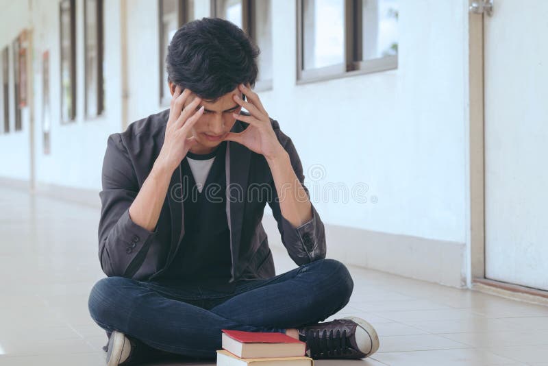 Étudiant asiatique s'asseyant sur la pièce avant, frustrée sur son travail et images stock Étudiant asiatique s'asseyant sur la pièce avant, frustrée sur son travail et images stock