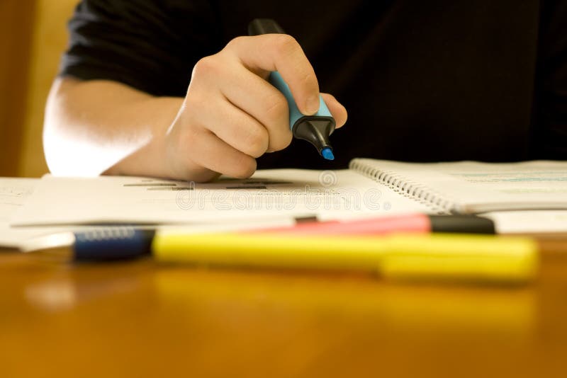 Hand of a student marking important words with a blue fluorescent marker. Studio lighting, two ambient strobes and a backlight. Hand of a student marking important words with a blue fluorescent marker. Studio lighting, two ambient strobes and a backlight.