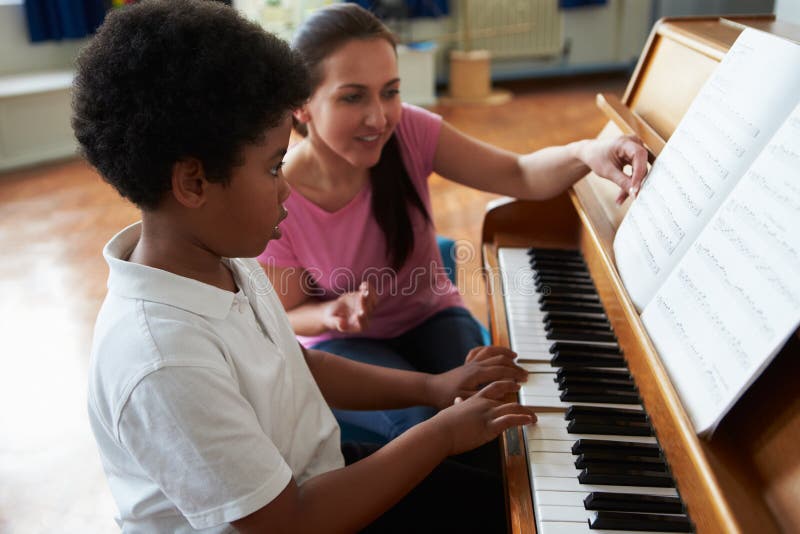 Étudiant masculin Enjoying Piano Lesson avec le professeur photo stock Étudiant masculin Enjoying Piano Lesson avec le professeur photo stock