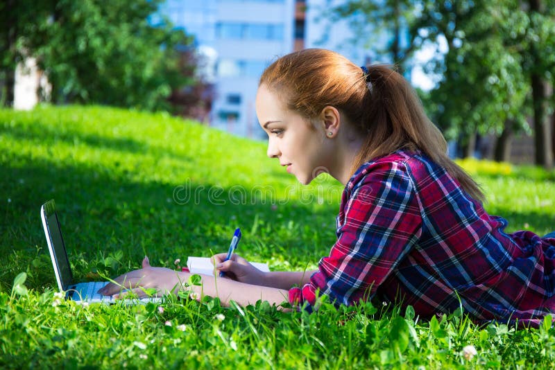 Étudiant ou fille adolescent d'école se situant en parc avec l'ordinateur portable images libres de droits Étudiant ou fille adolescent d'école se situant en parc avec l'ordinateur portable images libres de droits
