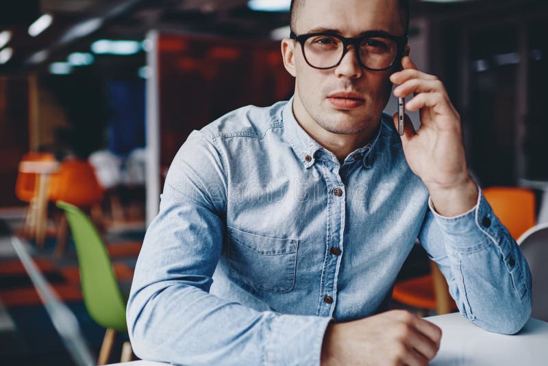 étudiant pensif hipster habillé en chemise denim parlant sur cellulaire photo libre de droits