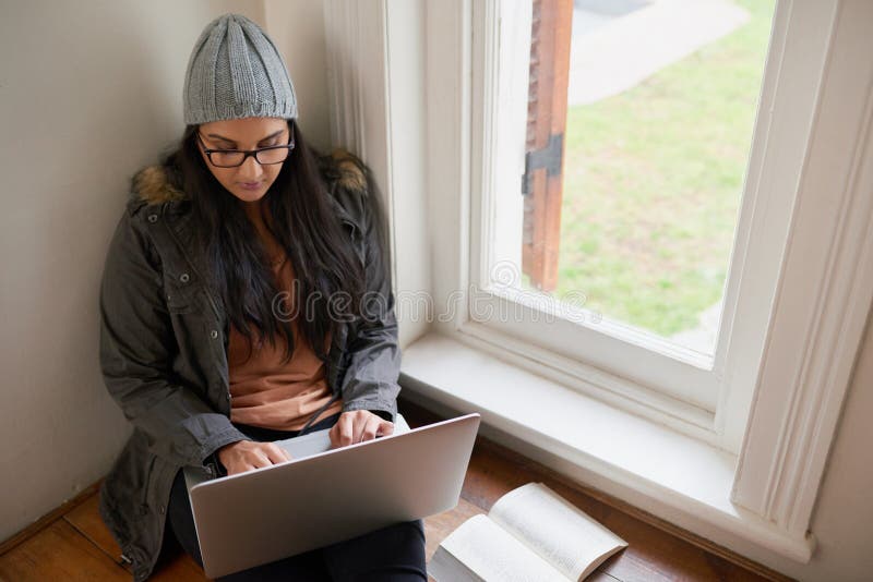 étudiante ou fille à domicile avec ordinateur par fenêtre pour la recherche littérature essai et projet d'affectation. connectivit photo libre de droits