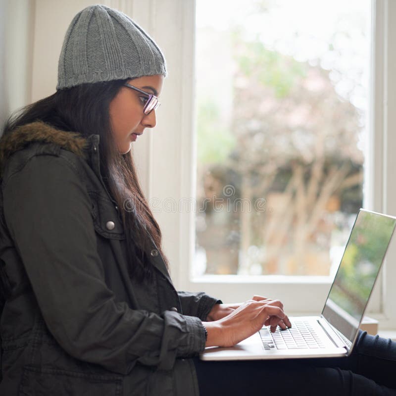 étudiante ou fille à domicile avec ordinateur portable par fenêtre pour la recherche littérature essai et projet d'affectation. co images stock