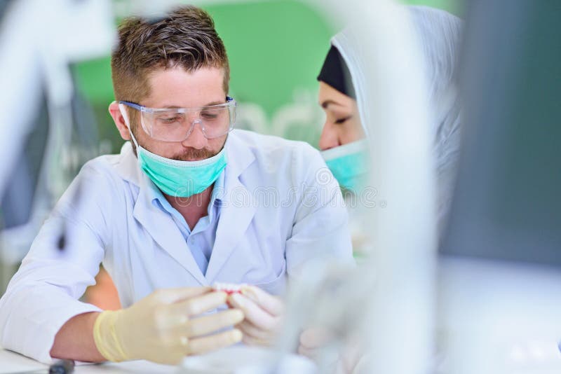 Étudiants arabes avec le hijab tout en travaillant au dentier, dents fausses photos libres de droits Étudiants arabes avec le hijab tout en travaillant au dentier, dents fausses photos libres de droits