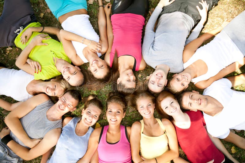 Smiling students lying on grass with their heads in a circle. Smiling students lying on grass with their heads in a circle