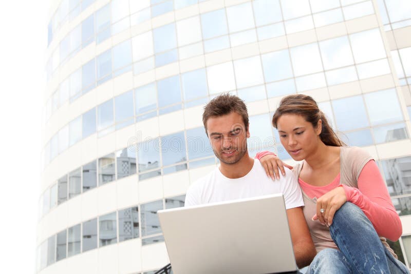 Couple of friends in college campus with laptop computer. Couple of friends in college campus with laptop computer