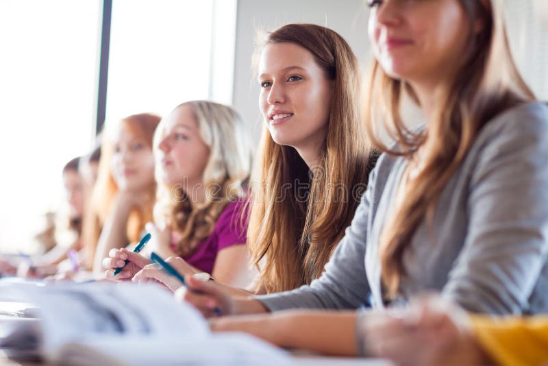 Étudiants dans la salle de classe - étudiant universitaire assez féminin de jeunes image stock Étudiants dans la salle de classe - étudiant universitaire assez féminin de jeunes image stock