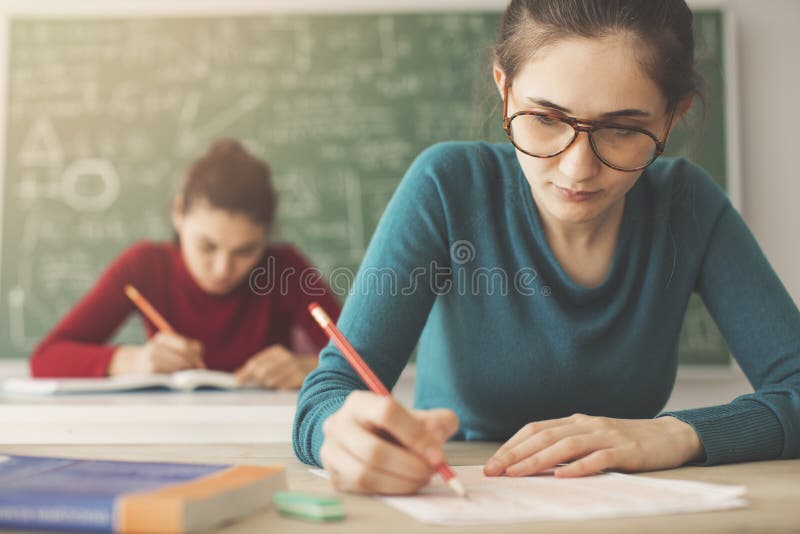 Étudiants prenant la réponse d'écriture d'examen dans la salle de classe photo stock Étudiants prenant la réponse d'écriture d'examen dans la salle de classe photo stock