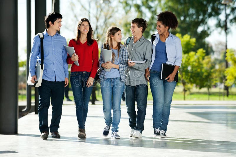 Full length of happy college students walking together on campus. Full length of happy college students walking together on campus