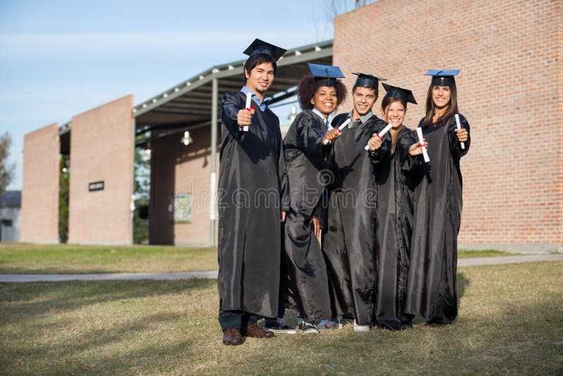Étudiants universitaires montrant des diplômes se tenant dessus image libre de droits Étudiants universitaires montrant des diplômes se tenant dessus image libre de droits