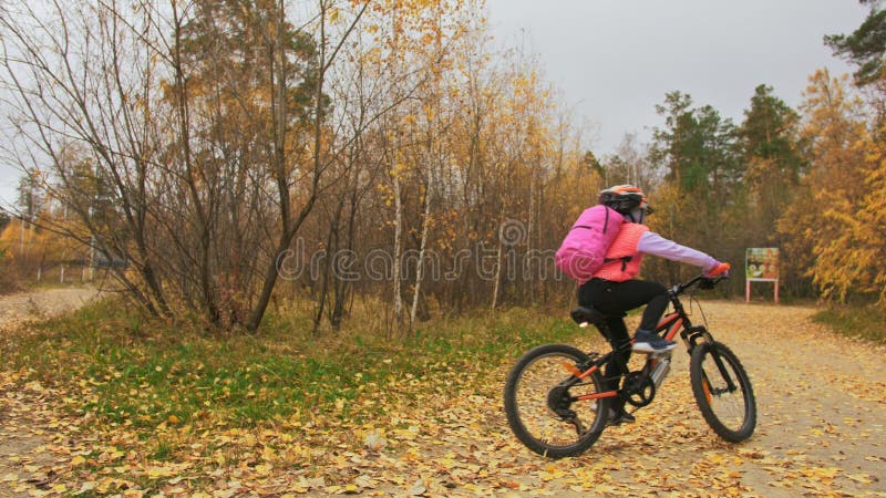 Één Kaukasische de fietsweg van kinderenritten in de herfstpark Het meisje die zwarte oranje cyclus in bosjong geitje berijden ga