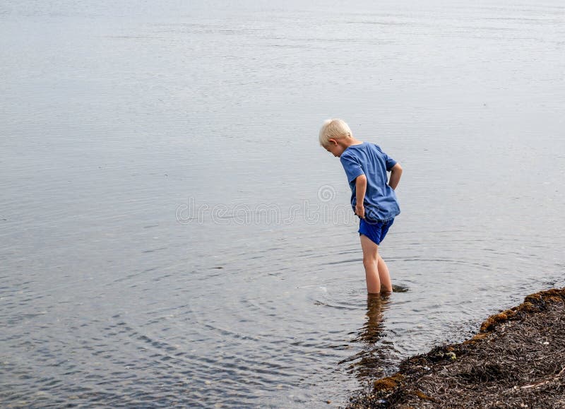 Één kleine jongen die in het water lopen
