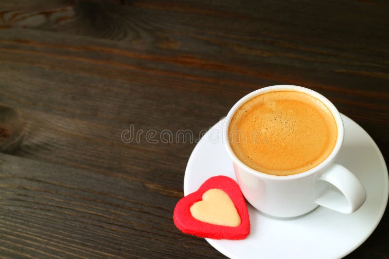 Één kop van hete espresso met een hart vormde koekje op donkere bruine houten lijst met exemplaarruimte stock afbeelding Één kop van hete espresso met een hart vormde koekje op donkere bruine houten lijst met exemplaarruimte stock afbeelding