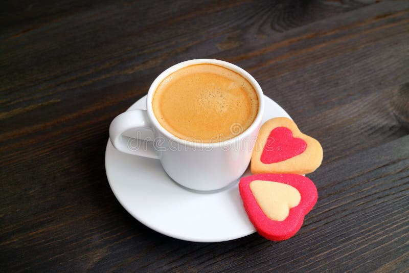 Één kop van hete koffie met een paar van hart vormde koekjes op donkere kleuren houten lijst stock foto's Één kop van hete koffie met een paar van hart vormde koekjes op donkere kleuren houten lijst stock foto's