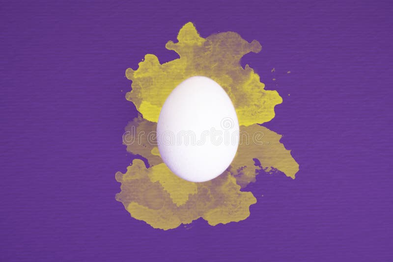 Één wit ei op ultraviolette achtergrond met gele waterverf ploetert stock afbeeldingen Één wit ei op ultraviolette achtergrond met gele waterverf ploetert stock afbeeldingen