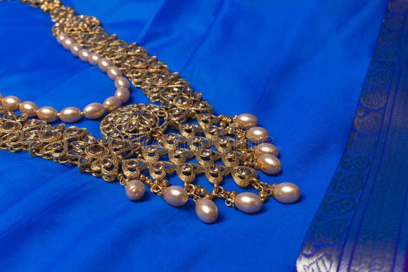 Indian traditional gold Indian wedding women`s jewelry on blue saree background. Close-up. Still-life. Indian traditional gold Indian wedding women`s jewelry on blue saree background. Close-up. Still-life.