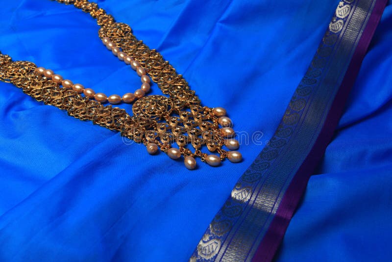 Indian traditional gold Indian wedding women`s jewelry on blue saree background. Close-up. Still-life. Indian traditional gold Indian wedding women`s jewelry on blue saree background. Close-up. Still-life.