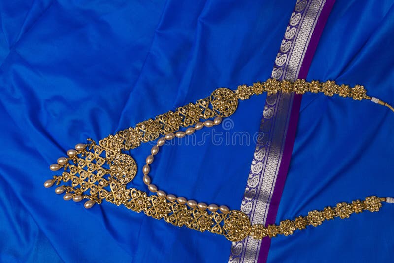 Indian traditional gold Indian wedding women`s jewelry on blue saree background. Close-up. Still-life. Indian traditional gold Indian wedding women`s jewelry on blue saree background. Close-up. Still-life.