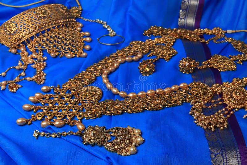 Indian traditional gold Indian wedding women`s jewelry on blue saree background. Close-up. Still-life. Indian traditional gold Indian wedding women`s jewelry on blue saree background. Close-up. Still-life.