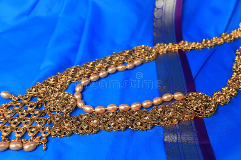 Indian traditional gold Indian wedding women`s jewelry on blue saree background. Close-up. Still-life. Indian traditional gold Indian wedding women`s jewelry on blue saree background. Close-up. Still-life.