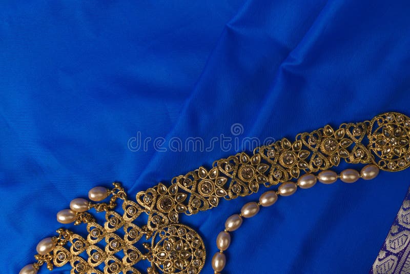 Indian traditional gold Indian wedding women`s jewelry on blue saree background. Close-up. Still-life. Indian traditional gold Indian wedding women`s jewelry on blue saree background. Close-up. Still-life.