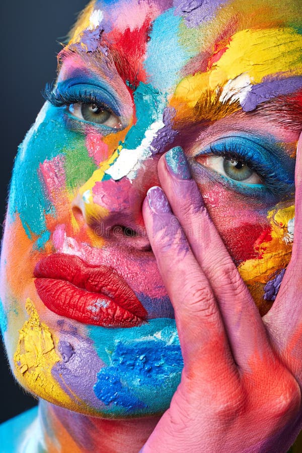 îmbrățișează orice culoare vorbește cu tine. O poză cu o tânără care se dă cu vopsea multicoloră pe față. royalty free stock images