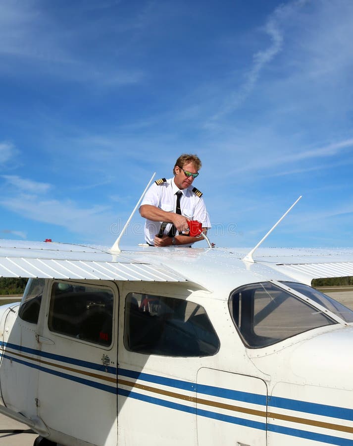 împușcat vertical de un om cu epoleți umplând aripile avionului cu combustibil pentru avioane royalty free stock image