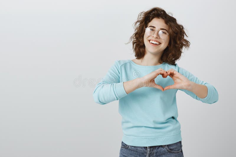 împărtășirea iubirii cu persoane apropiate. femeie tânără și veselă în ochelari de trendy și bluză albastră care arată gestul card royalty free stock photos