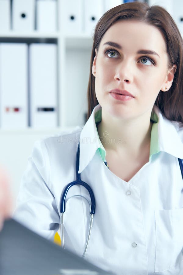 în cauză, o femeie doctor în medicina muncii, ascultând cu atenție plângerile pacienților în cadrul unui cabinet medical. asistenț stock images